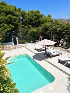 a swimming pool with two lounge chairs and an umbrella at seaview apartment - villa a’more in Milna +32 photos