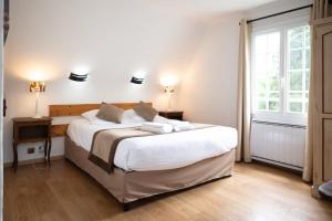 a bedroom with a large white bed with two lamps at Logis Hôtels - Hôtel Restaurant Domaine Les Falaises in Martel