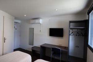 a bedroom with a desk and a bed and a tv at Brit Hotel Montpellier Eurom&eacute;decine in Montpellier