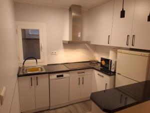 a kitchen with white cabinets and a black counter top at Apartamento El Cortijo in Ateca