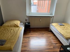 two beds in a small room with a window at Geräumige Appartements in Osnabrück in Osnabrück