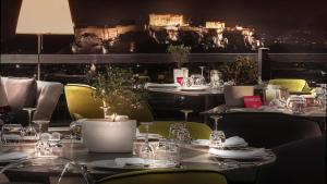 een eetkamer met tafels en stoelen met verlichting bij St George Lycabettus Lifestyle Hotel in Athene