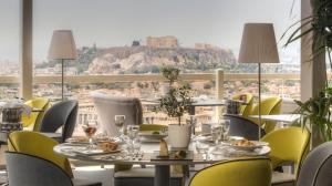 a restaurant with a table and chairs with a view ofhens at St George Lycabettus Lifestyle Hotel in Athens +85 photos