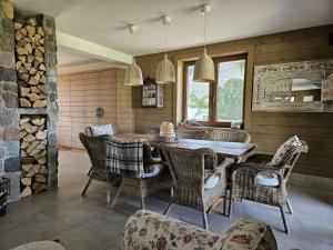 a dining room with a table and wicker chairs at Azyl Apetytu in Filipów
