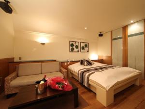 京都Hotel La Siesta (Adult Only)的一间卧室，里面有一张床、一张沙发和一张桌子