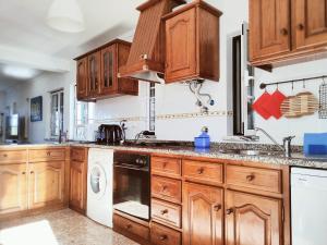 una cucina con armadi in legno, lavatrice e asciugatrice di Casa Lagoa Mar a Costa de Santo André Altre 25 foto