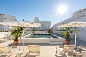 a pool with chairs and umbrellas on a building at Estudios Salinas - Fuseta in Fuzeta