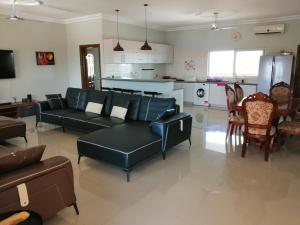 a living room with a black couch and a kitchen at GUSSYS Homes in Cape Coast