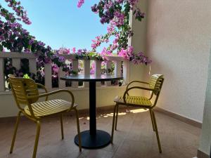 two chairs and a table in a balcony with flowers at Apartments Villa Čizmić in Baška Voda