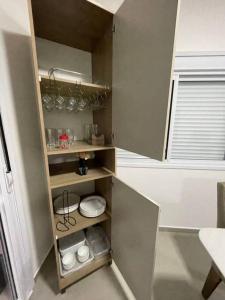 a small kitchen with wooden shelves and dishes in it at Riviera de Garopaba Unidade Azure - A Beira Mar in Garopaba