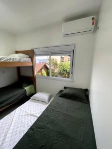 a room with two bunk beds and a window at Riviera de Garopaba Unidade Azure - A Beira Mar in Garopaba