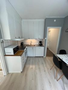 a kitchen with white cabinets and a sink and a table at Prisvärd & rymlig lgh nära ALV in Vimmerby