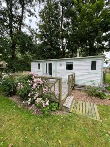 a small white caravan in a yard with flowers at Auberge de Keringar in Le Conquet