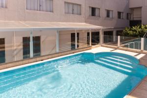 a swimming pool in front of a building at Califórnia Suítes in Belo Horizonte