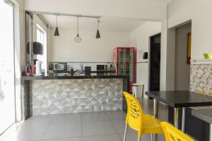 a kitchen with a table and yellow chairs in a room at Califórnia Suítes in Belo Horizonte