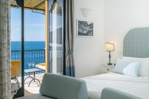 波西塔诺Albergo Miramare Positano的一间带床的卧室和一个可欣赏海景的阳台