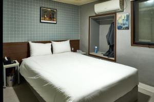 a bedroom with a white bed and a mirror at Hyuzen Hotel - 휴젠 in Seoul