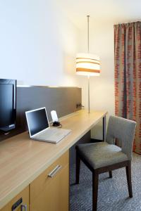 um computador portátil sentado numa secretária com uma cadeira em Holiday Inn Essen City Centre, an IHG Hotel em Essen