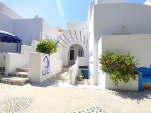 a view of a white building with flowers in a courtyard at Chariot Apartments Santorini in Kamari