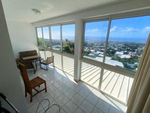 une pièce avec de grandes fenêtres avec un bureau et une table dans l'établissement Kaze Bretagne - Évasion à Saint-Denis - Charmante Maison T3 avec Terrasse, Jardin et Vue Imprenable - Proche Aéroport, à Saint-Denis