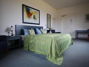 a bedroom with a bed with a green bedspread at Hotel & Restaurant Schloss Weißenburg in Uhlstädt