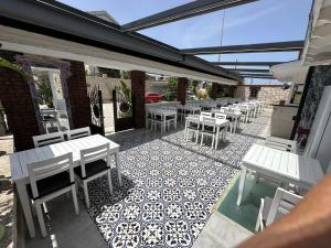 a patio with white tables and chairs on a building at Grand Alaçatı Butik Hotel in Alaçatı