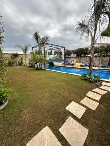 a resort yard with a swimming pool and palm trees at Grand Alaçatı Butik Hotel in Alaçatı