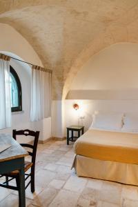 a bedroom with a bed and a table in a room at Masseria Gorgognolo in Ostuni
