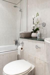 a white bathroom with a toilet and a sink at Spacious 1 Bed Sloane Square in London +31 photos
