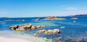 a group of rocks in the water next to a beach at Piso vistas al mar 2. Playa Aguete. Rías Baixas in Marín