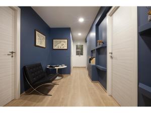 un couloir avec une chaise noire et un mur bleu dans l'établissement Alex's Guest House, à Rome