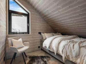 a bedroom with a bed and a chair and a window at Flygende utsiktshytte med magisk utsikt in Sogndal