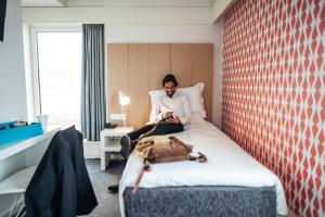 a man sitting on a bed with a dog laying on it at Stay Hotel Porto Centro Trindade in Porto