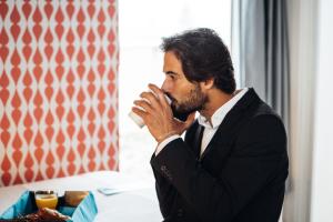 a man in a suit drinking a cup of coffee at Stay Hotel Porto Centro Trindade in Porto