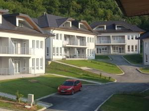 a red car parked in a parking lot in front of apartment complexes at Countryside Resort Sarajevo in Hadžići