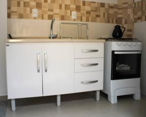 a white kitchen with a sink and a stove at Riviera de Garopaba Unidade Lumina - A Beira Mar in Garopaba +43 photos