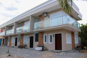 a building with a balcony and a palm tree at Riviera de Garopaba Unidade Lumina - A Beira Mar in Garopaba