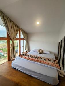 ein Bett in einem Zimmer mit einem großen Fenster in der Unterkunft Cottage linggayoni Dieng 2 in Diyeng