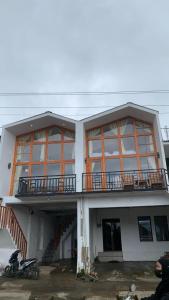 ein Gebäude mit einem Balkon und einem Roller, der vorne geparkt ist in der Unterkunft Cottage linggayoni Dieng 2 in Diyeng