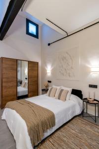 a bedroom with a large white bed and a mirror at Loft Suite Frutos in Seville