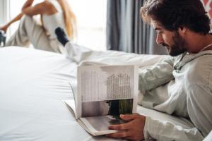 a man laying on a bed reading a book at Stay Hotel Porto Centro Trindade in Porto