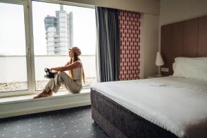 a woman sitting on a window sill in a hotel room at Stay Hotel Porto Centro Trindade in Porto