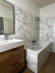 a bathroom with a sink and a tub and a mirror at H&ocirc;tel Saint-Julien in Angers