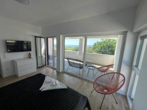 a bedroom with a bed and a balcony with chairs at Innova TravelVir - Villa SunSet in Privlaka