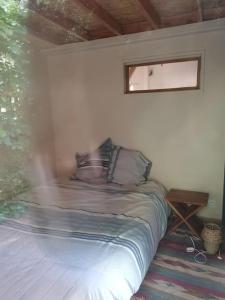 Una cama pequeña en una habitación con ventana. en le logis en bois, en Saint-Mathieu-de-Tréviers