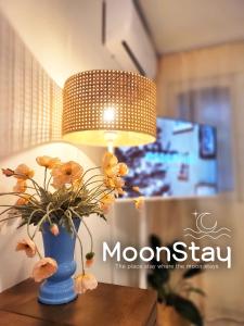 a blue vase with flowers on a table with a lamp at MoonStay in Seoul