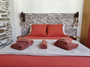 a bed with red pillows and towels on it at Appartement T1 centre-ville Beaupréau in Beaupréau