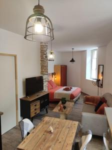a living room with a couch and a bed and a table at Appartement T1 centre-ville Beaupréau in Beaupréau