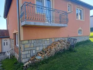 a building with a balcony and a pile of fire wood at Apartmani Drndić Sjenica in Sjenica +7 photos