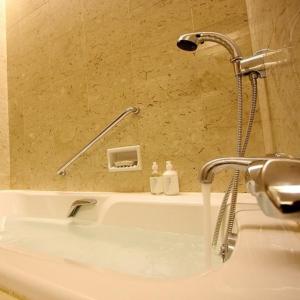 a bath tub with a shower with water coming out of it at Hotel de Premiere Minowa in Inawashiro